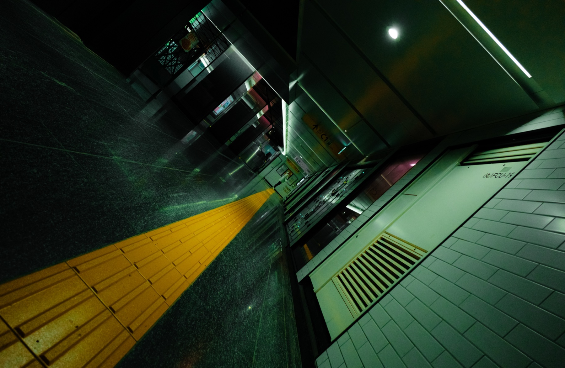 A tilted night view of a green-lit underground passage