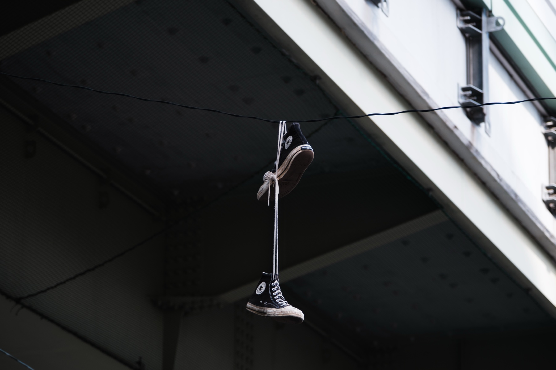 A pair of sneakers hanging from a wire beneath a bridge