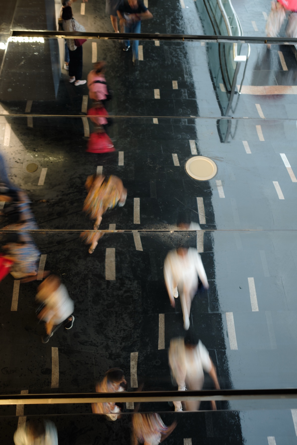 A crowd blurred in motion, reflected in a polished floor