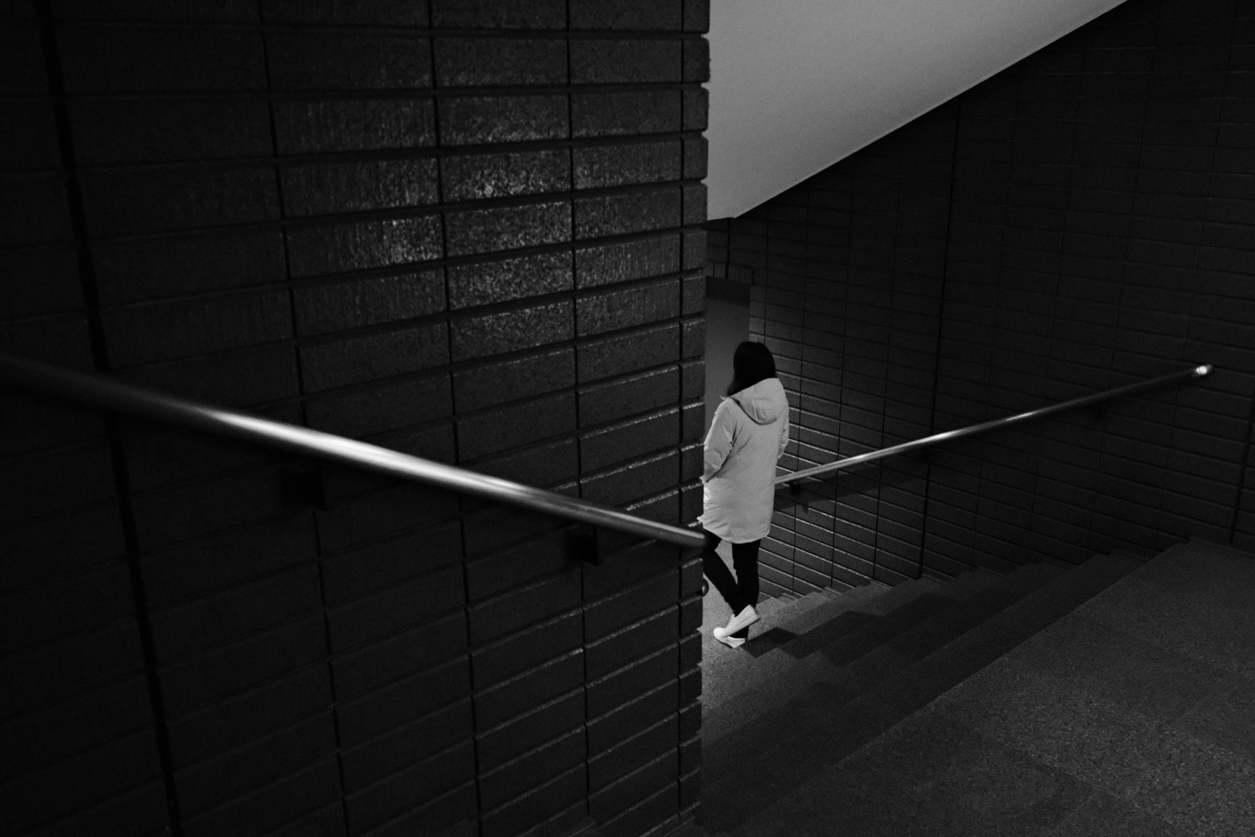 A figure in a white coat descending a dim stairwell
